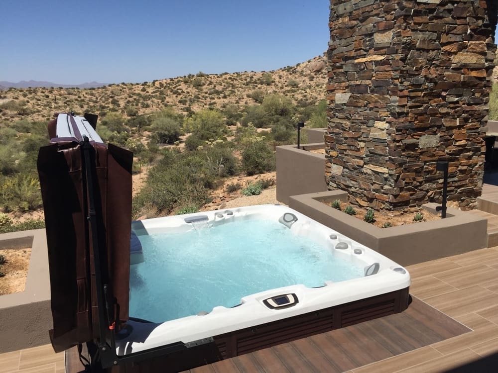 Outdoor hot tub with stone chimney and desert view
